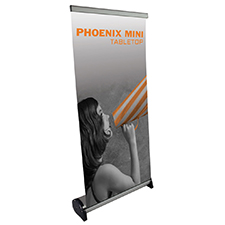 Phoenix Mini retractable tabletop banner stand with ZeroCurl banner on a table.